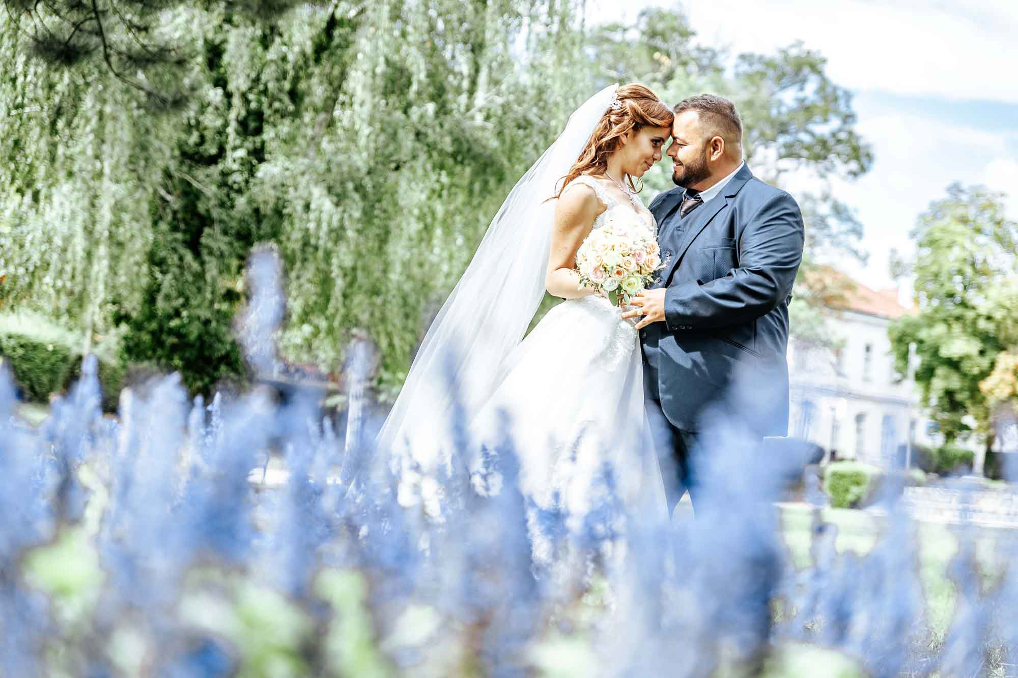 Friss házasok csókot váltanak a virágok mögött